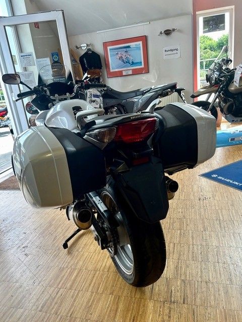 Motorrad mit Seitenkoffern, geparkt in einem Ausstellungsraum, Ansicht von hinten.