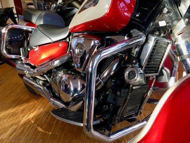 Ein rot-weißes Motorrad ist auf einem Holzboden geparkt