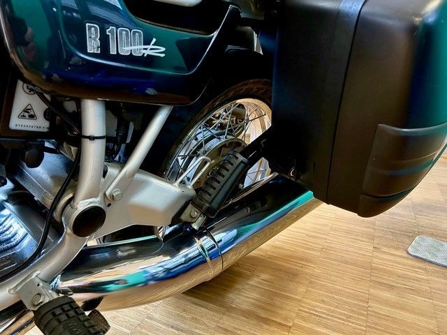 Eine Nahaufnahme des Auspuffrohrs eines Motorrads auf einem Holzboden.