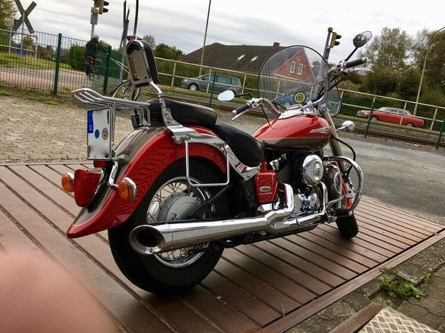 Ein rotes Motorrad ist auf einem Holzdeck geparkt