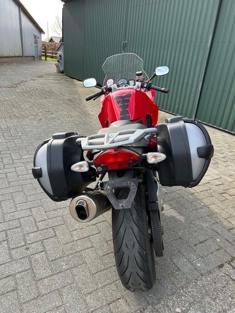 Vor einem grünen Gebäude parkt ein rotes Motorrad.