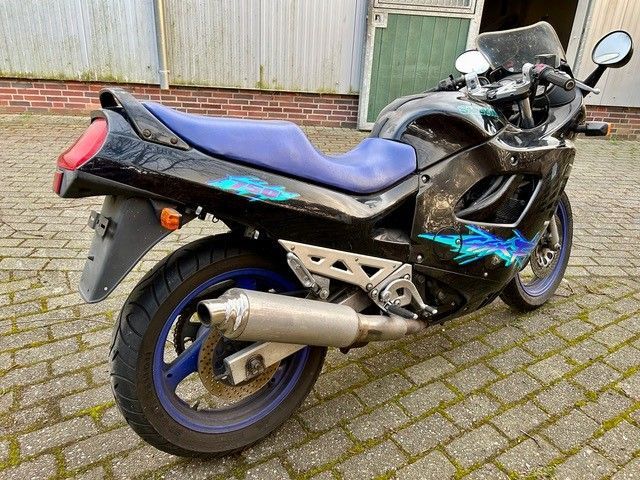 Auf einer gepflasterten Auffahrt ist ein schwarz-blaues Motorrad geparkt.