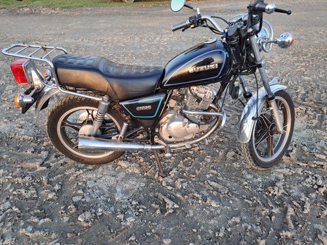 Ein schwarzes Suzuki-Motorrad ist auf einer unbefestigten Straße geparkt