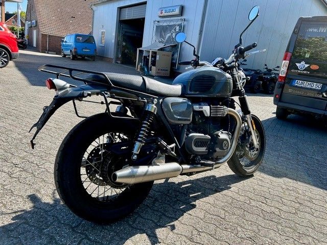 Auf einem Parkplatz steht neben einem Lieferwagen ein schwarzes Motorrad.