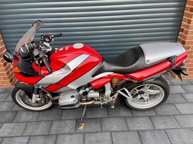 Ein rot-silbernes Motorrad steht vor einem Garagentor