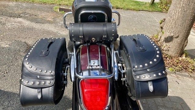 Ein Motorrad mit schwarzen Ledersatteltaschen ist am Straßenrand geparkt.