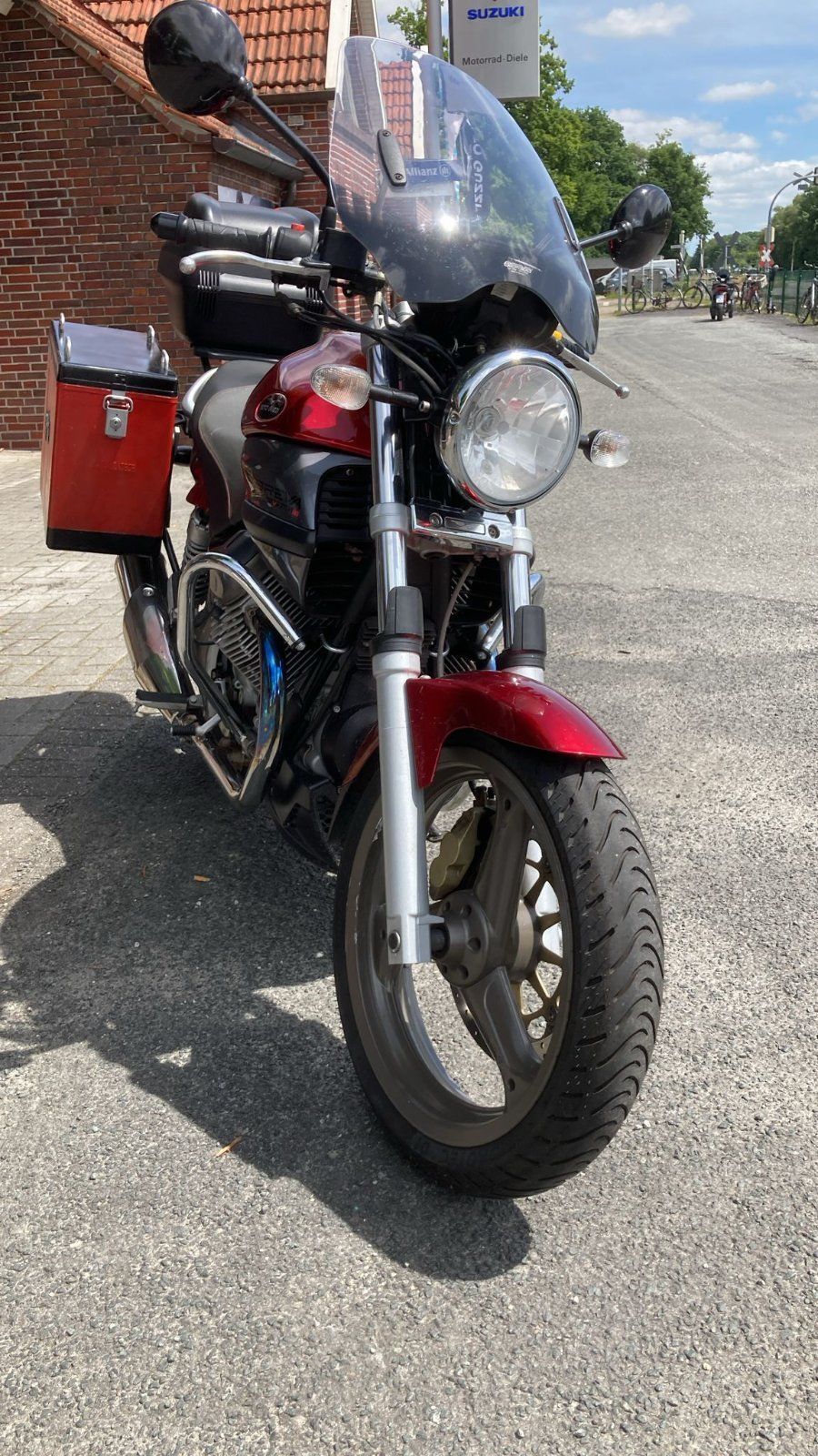 Ein rot-schwarzes Motorrad ist am Straßenrand geparkt.