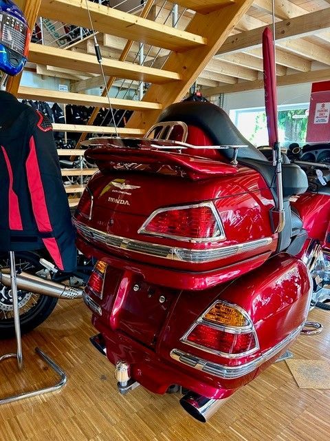 Rotes Honda Goldwing-Motorrad in einem Ausstellungsraum. Mit Gepäckfächern, Chromakzenten und in der Nähe einer Holztreppe.