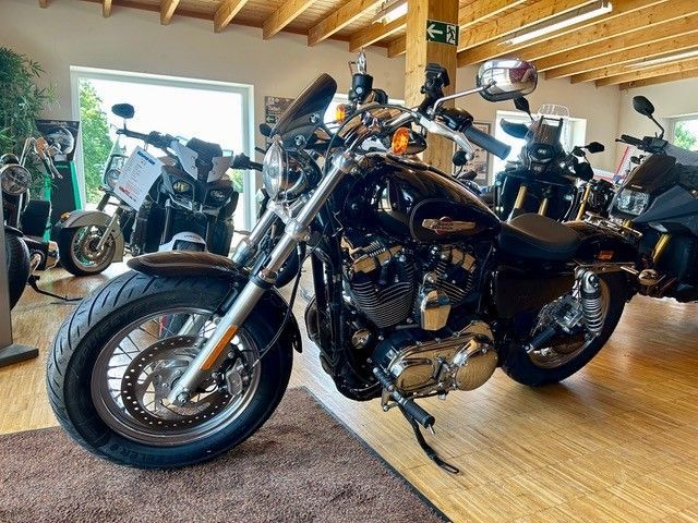 Schwarzes Motorrad in einem Ausstellungsraum mit anderen Motorrädern und Holzbalken an der Decke.