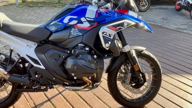 Auf einem Holzboden ist ein blau-weißes Motorrad geparkt.