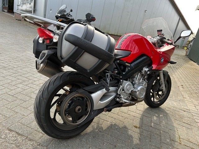 Ein rotes Motorrad ist auf einem gemauerten Bürgersteig geparkt