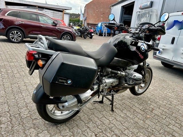 Schwarzes BMW-Motorrad mit Seitenkoffern, auf Ziegelstein geparkt.