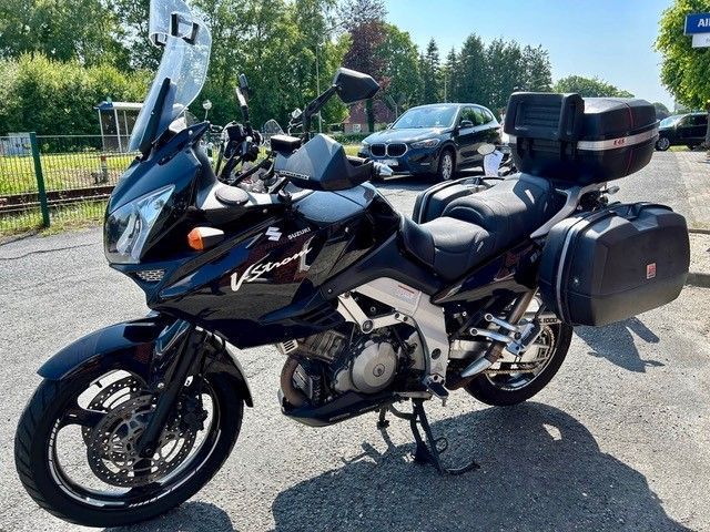 Ein schwarzes Motorrad ist am Straßenrand neben einem Auto geparkt.