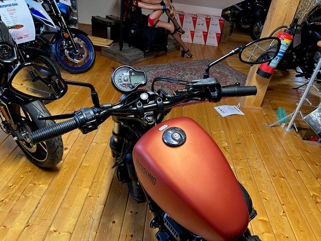Ein rotes Motorrad ist auf einem Holzboden geparkt