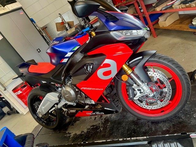 Rotes und blaues Sportmotorrad in einer Garage, Seitenansicht auf nassem Boden