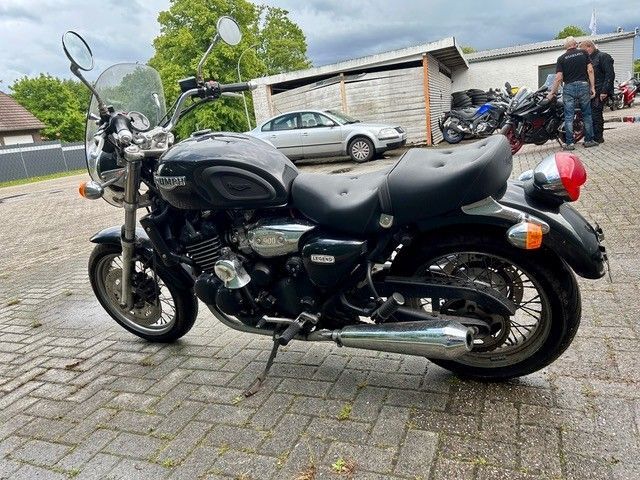 Ein schwarzes Motorrad parkte auf einer gepflasterten Auffahrt vor einer Garage und Wohnhäusern.