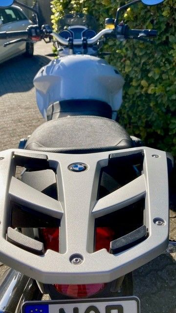 Rückansicht eines weißen BMW-Motorrads mit Gepäckträger, Nummernschild und Rücklicht.