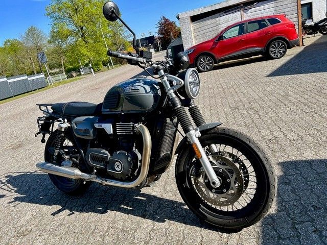 Auf einem Parkplatz steht neben einem roten Auto ein Motorrad.