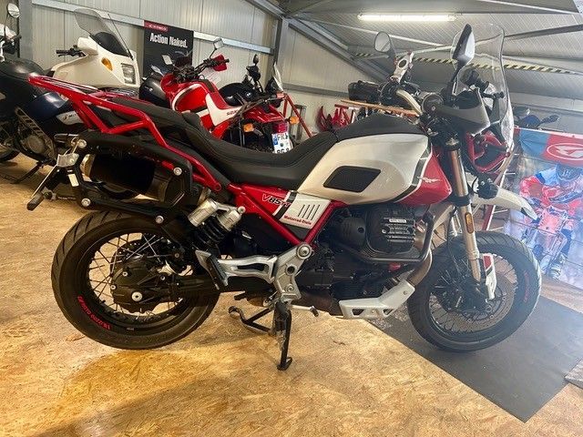 Ein weiß-rotes Motorrad parkt in einem Ausstellungsraum, im Hintergrund sind weitere Motorräder zu sehen.