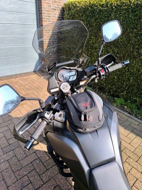 Schwarzes Motorrad-Armaturenbrett mit Windschutzscheibe, Spiegeln und Tankrucksack, im Freien.