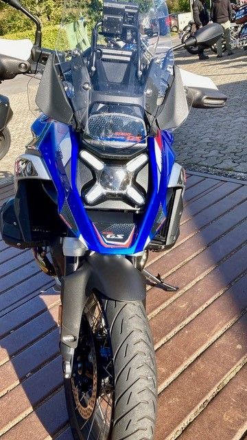 Auf einem Holzdeck ist ein blau-schwarzes Motorrad geparkt.