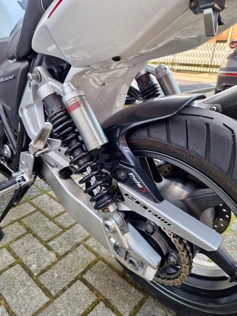 Rückansicht eines Motorrads mit Stoßdämpfer, schwarzem Reifen und Schwinge.