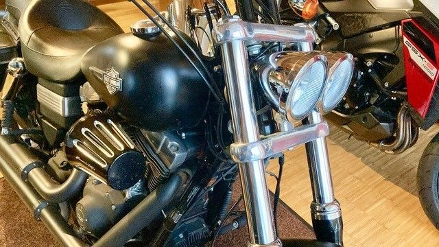 Ein schwarzes Harley-Davidson-Motorrad ist auf einem Holzboden geparkt.