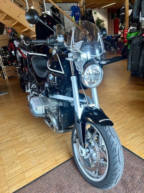Schwarzes Cruiser-Motorrad mit Windschutzscheibe, in einer Halle auf Holzboden geparkt, Vorderansicht.