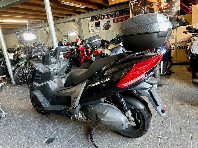 Ein schwarzer Roller steht in einem Motorrad-Showroom, im Hintergrund sind weitere Motorräder zu sehen.