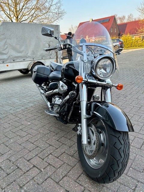 Ein schwarzes Motorrad mit Windschutzscheibe ist auf einer Ziegelstraße geparkt