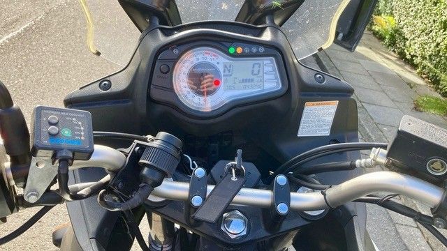 Armaturenbrett eines Motorrads mit Anzeigen und Bedienelementen aus der Perspektive des Fahrers. Beinhaltet Tachometer, Tankanzeige und andere Anzeigen.