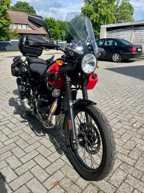 Schwarzes Motorrad mit Windschutzscheibe parkt im Sonnenlicht auf einer Kopfsteinpflasterstraße.