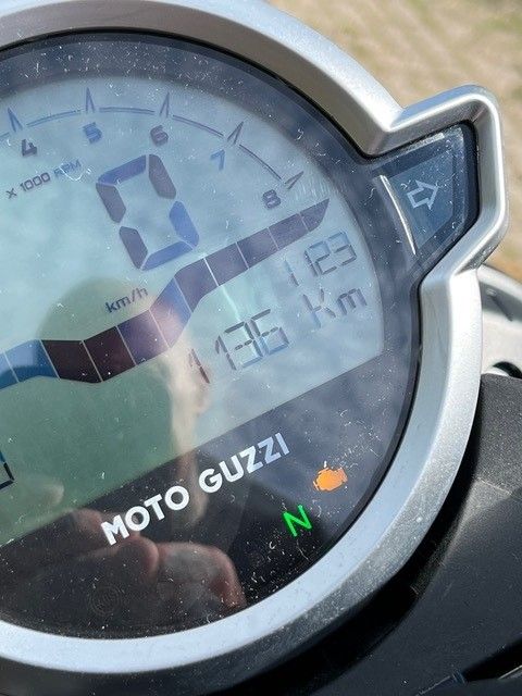 Motorrad-Armaturenbrett mit Geschwindigkeitsanzeige bei 0, 136 km/h, Gesamtkilometerzahl 1123, mit Moto Guzzi-Logo und Motorleuchte.