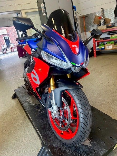 Blaues und rotes Sportmotorrad in einer Garage, vorne links auf einer Plattform.