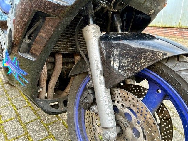 Eine Nahaufnahme der Vorderseite eines Motorrads, das auf einer Ziegelsteinstraße geparkt ist.