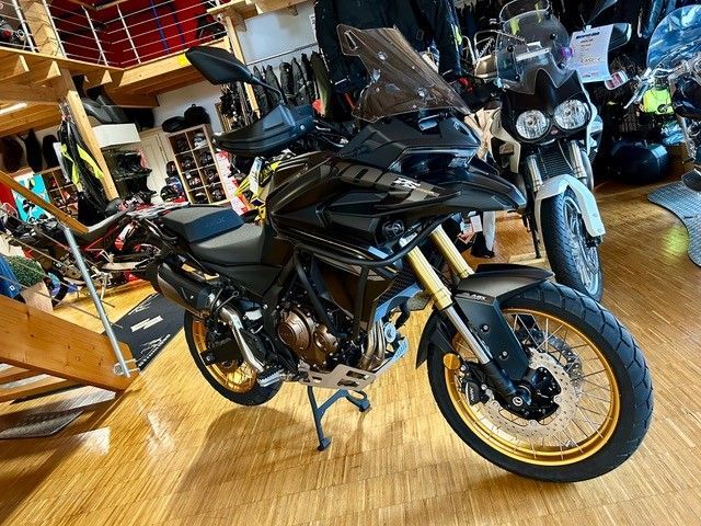 In einem Ausstellungsraum ist ein Motorrad auf einem Holzboden geparkt.