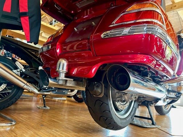 Rotes Motorrad mit verchromten Auspuffrohren und Anhängerkupplung; drinnen geparkt.