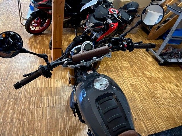 In einem Ausstellungsraum ist ein Motorrad auf einem Holzboden geparkt.