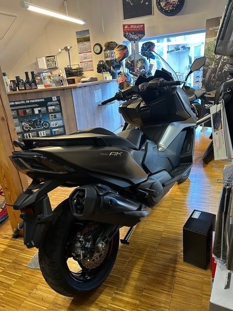 In einem Ausstellungsraum steht neben einer Theke ein Motorroller.