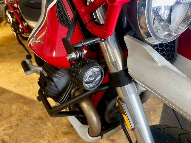 Nahaufnahme der Frontpartie eines roten Motorrads mit Scheinwerfer, Gabel und Motordetails in einem Innenraum
