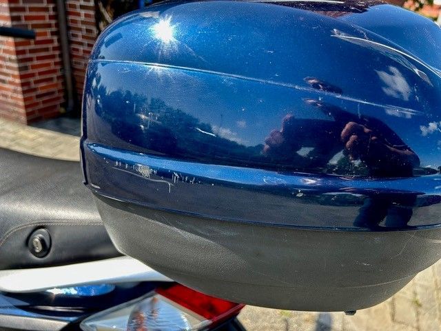 Ein blaues Motorrad steht vor einem Backsteingebäude