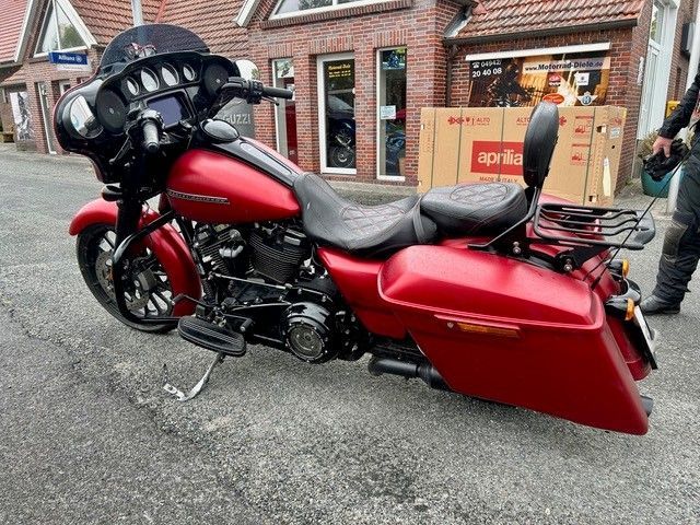 Ein rotes Tourenmotorrad parkte auf einer nassen Straße vor Backsteinhäusern.