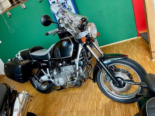 Ein schwarzes Motorrad ist auf einem Holzboden in einem Raum geparkt.