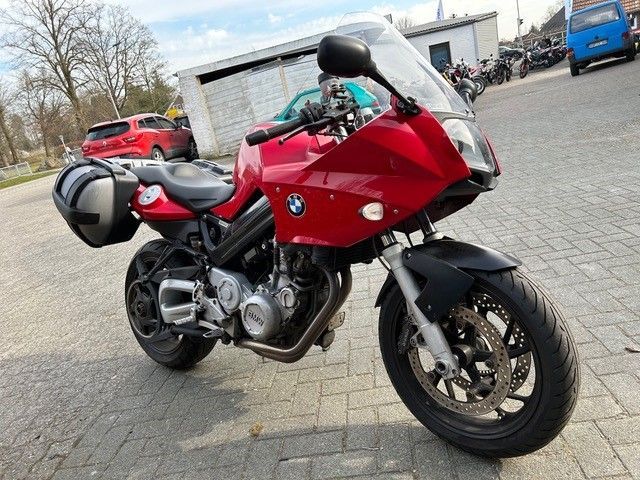 Auf einer Ziegelsteinstraße parkt ein rotes Motorrad.