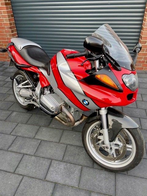 Ein rotes BMW-Motorrad steht vor einem Garagentor