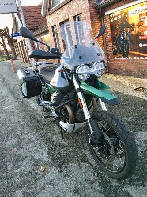 Vor einem Backsteingebäude parkt ein grünes Motorrad.