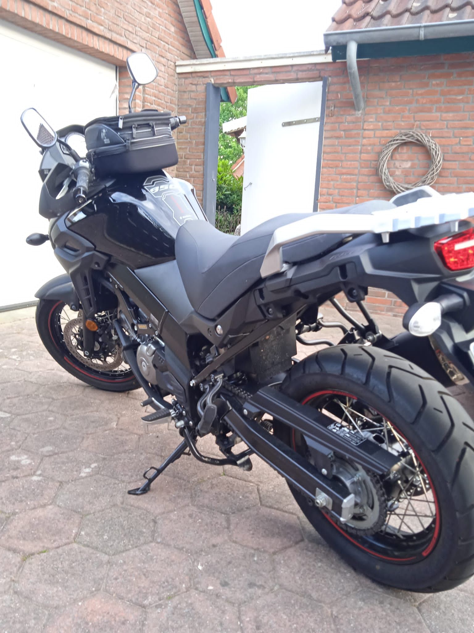 Vor einem Backsteingebäude parkt ein schwarzes Motorrad.