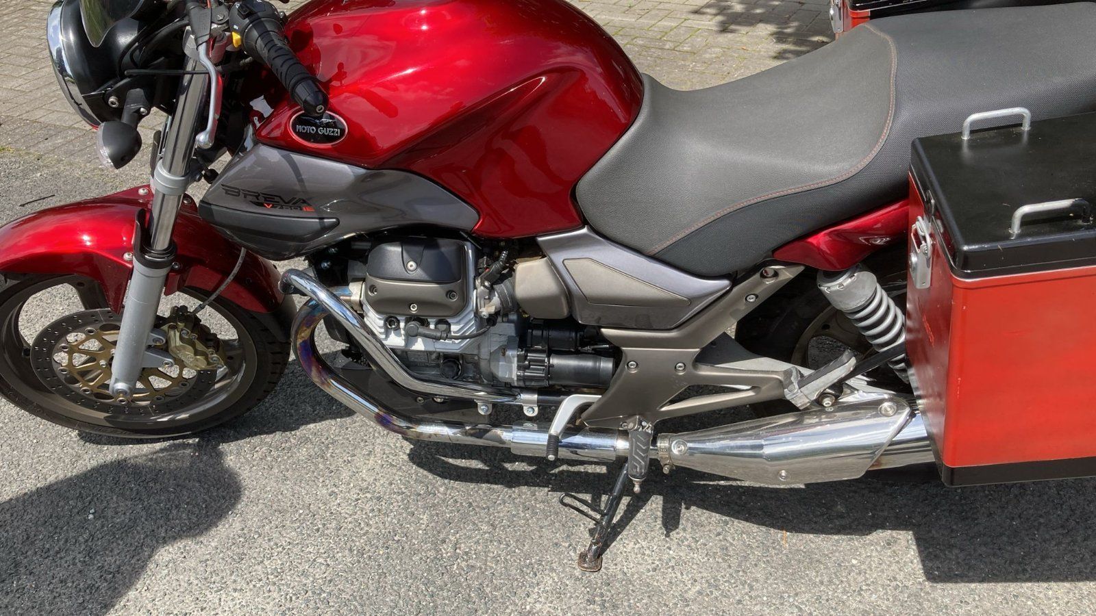 Ein rotes Motorrad ist am Straßenrand geparkt.