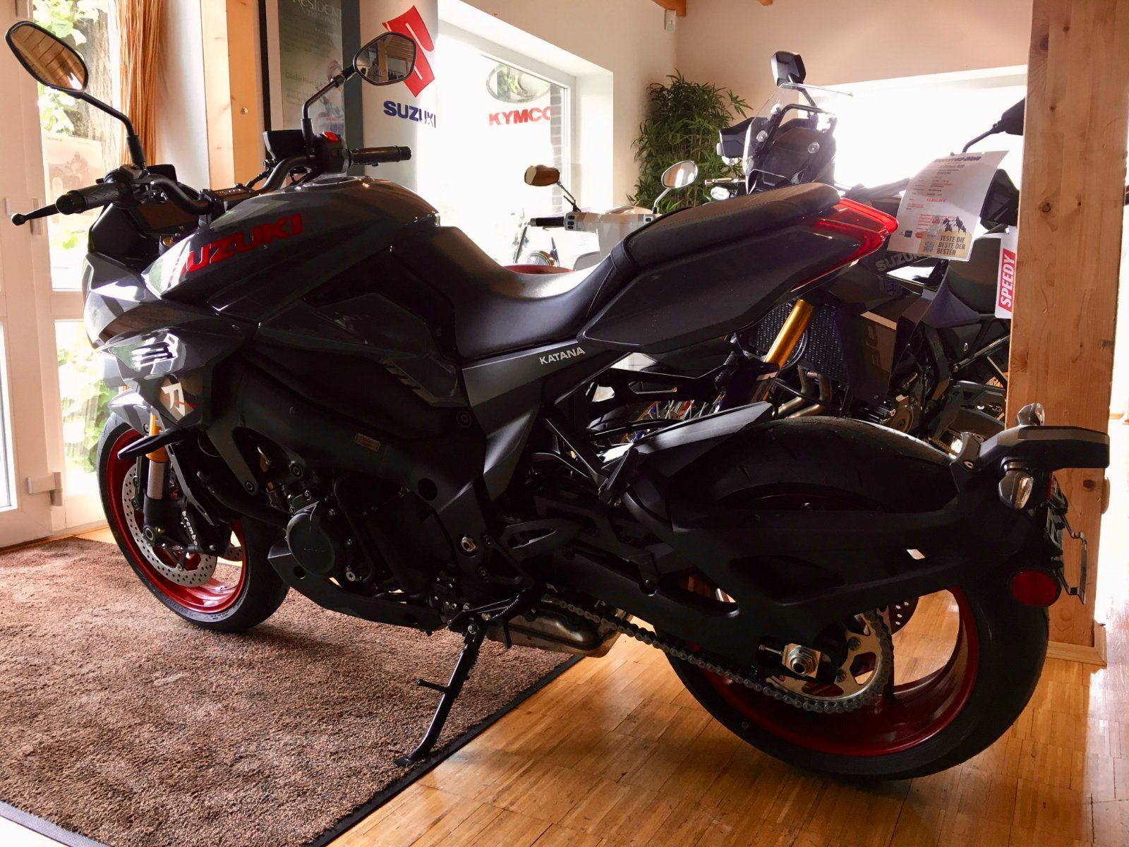 In einem Raum ist ein schwarzes Motorrad mit roten Rädern geparkt.