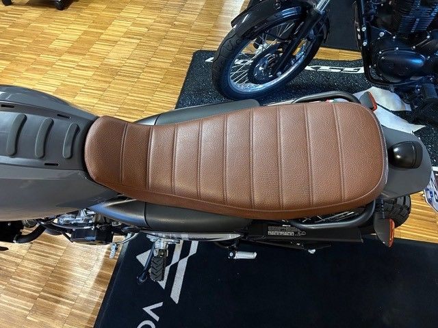 In einem Ausstellungsraum steht ein Motorrad mit braunem Sitz.